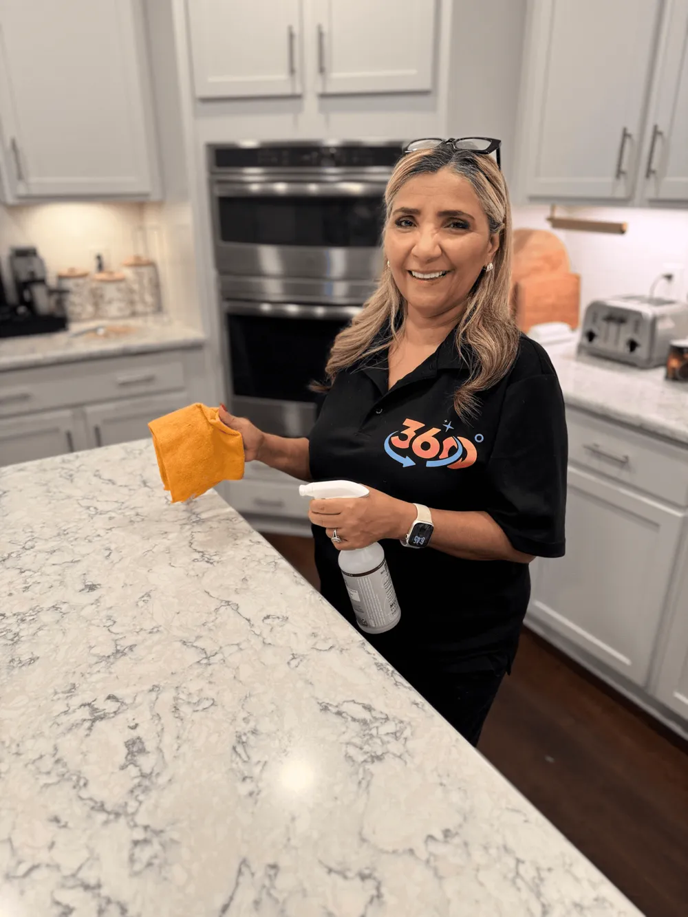 Martha Lembert, owner of 360 Cleaning, in a kitchen wearing a 360 Cleaning shirt
