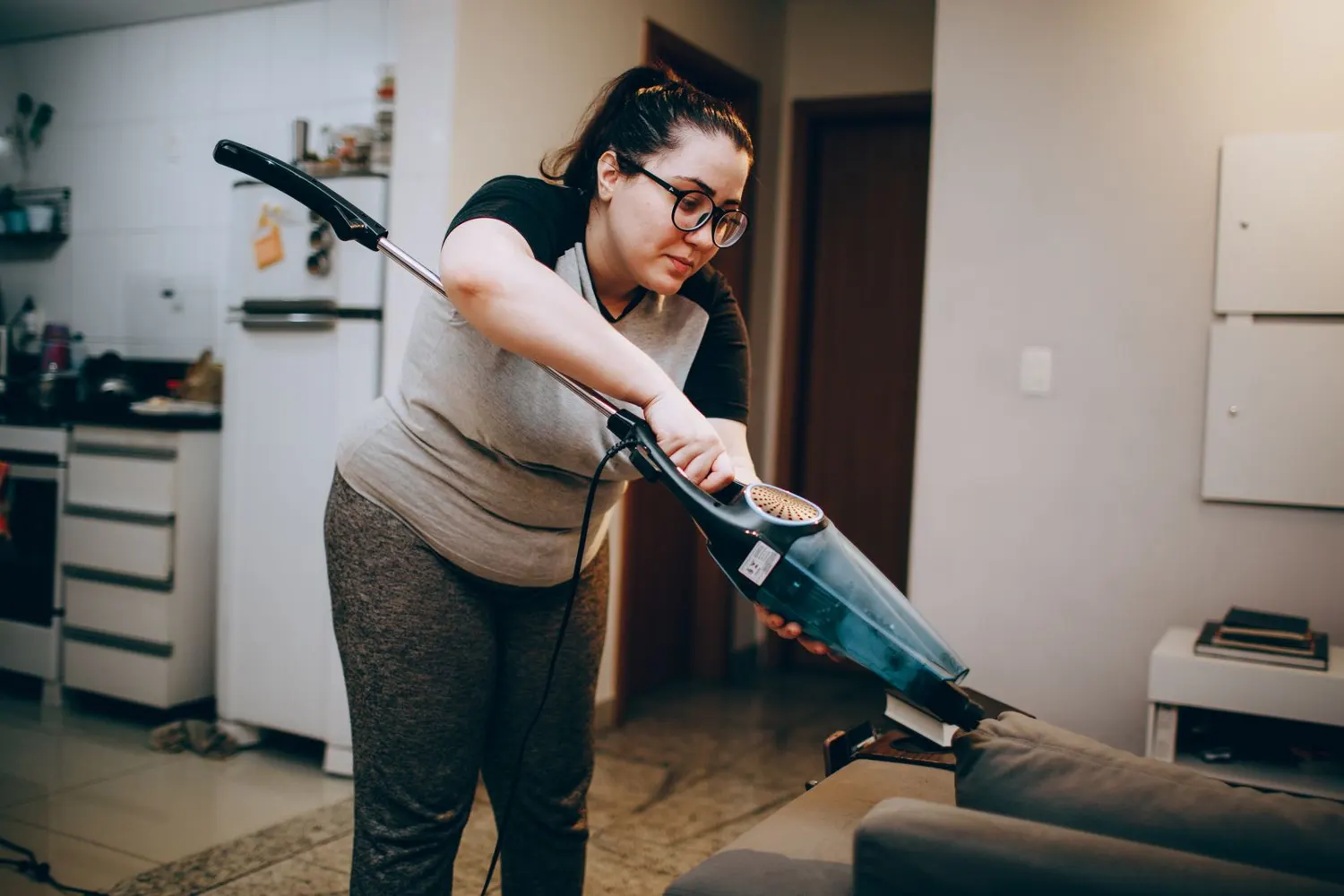 Stock photo of a woman vacuuming a sofa in a living room