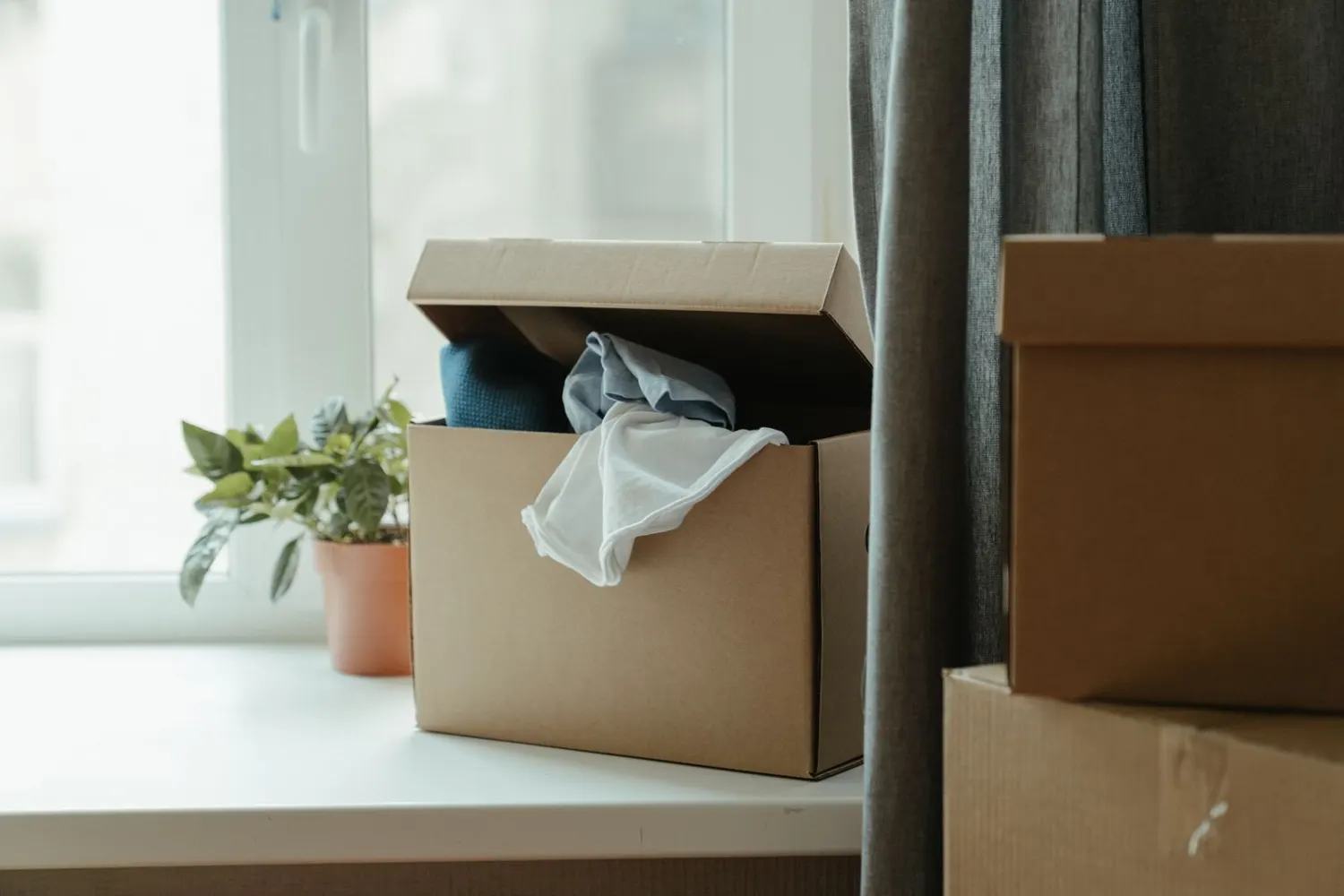 Stock photo of an open moving box beside a window