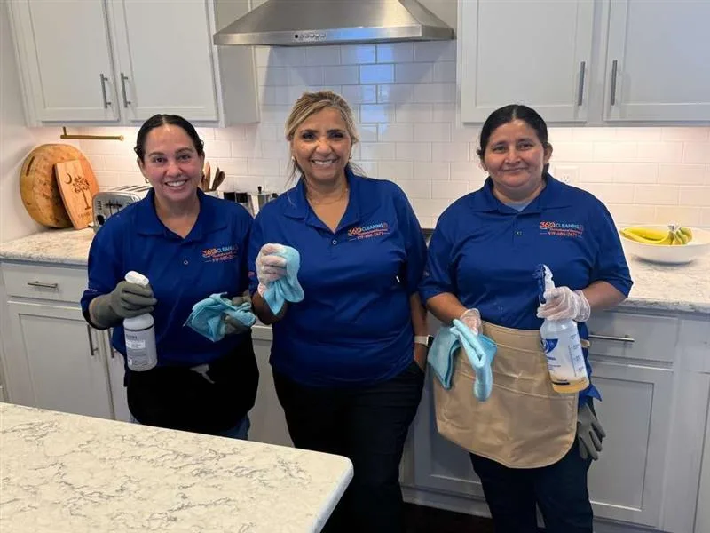 Martha and two members of the 360 Cleaning team in a kitchen, holding spray bottles and cloths